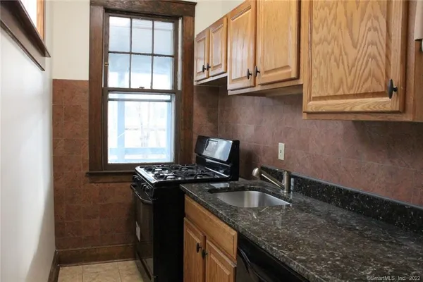 a kitchen with granite countertop stainless steel appliances a sink stove and cabinets