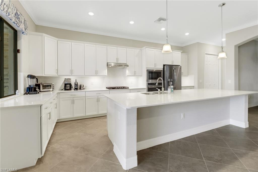 1878 Mustique Street Naples, FL 34120 - Photo 13 of 50 a kitchen with kitchen island a sink stainless steel appliances and cabinets