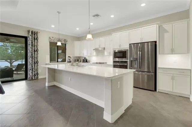 a large kitchen with a large counter top stainless steel appliances and cabinets