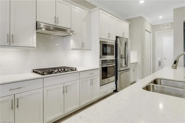 a kitchen with stainless steel appliances granite countertop a sink a stove and refrigerator