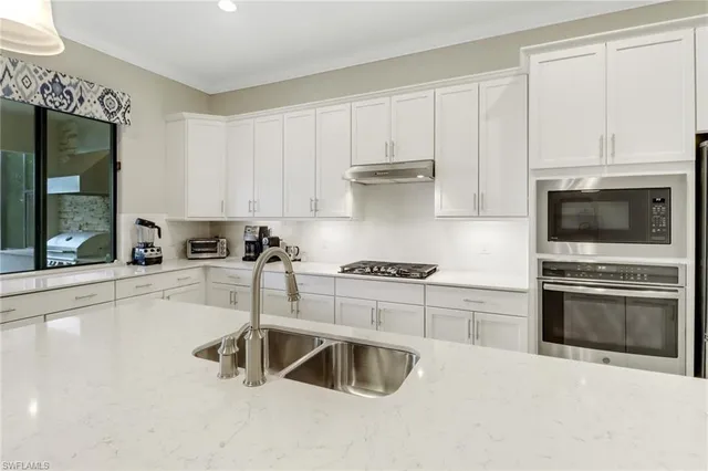 a kitchen with granite countertop a stove a sink and a microwave