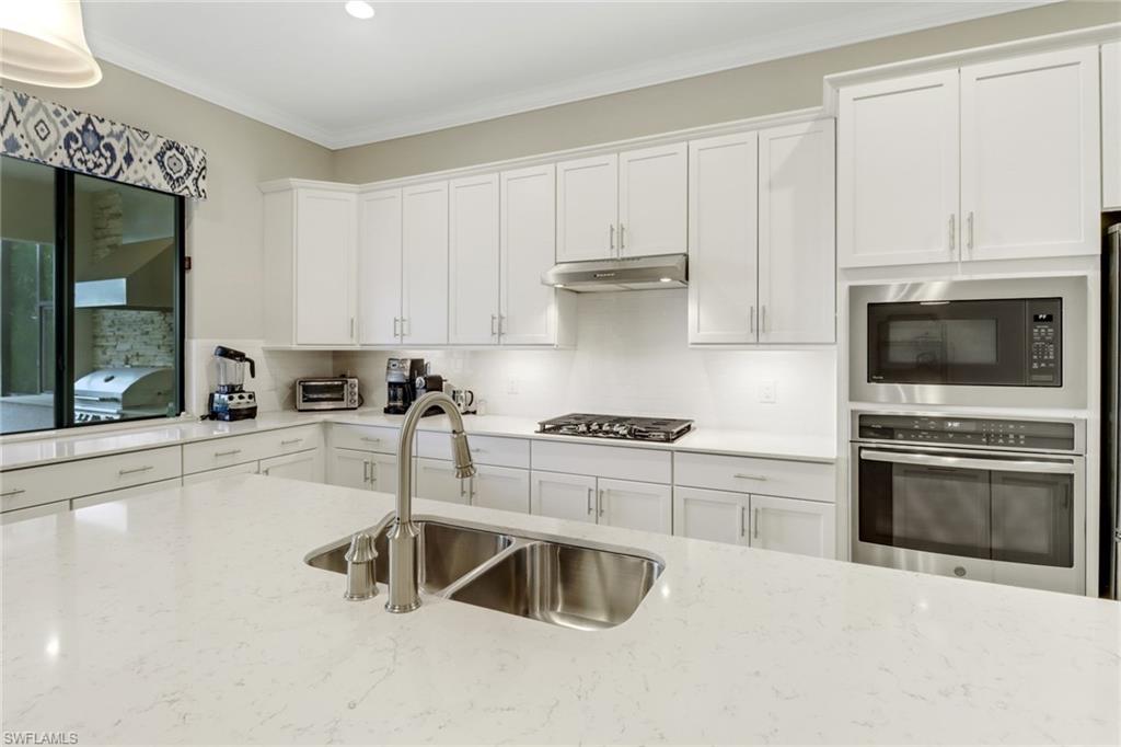 1878 Mustique Street Naples, FL 34120 - Photo 17 of 50 a kitchen with granite countertop a stove a sink and a microwave