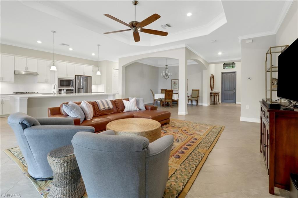 1878 Mustique Street Naples, FL 34120 - Photo 10 of 50 a living room with furniture a flat screen tv and kitchen view
