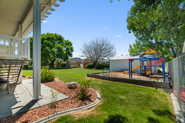 5727 South 3550th Street West Roy, UT 84067 - Photo 32 of 49 Expansive green lawn featuring a dedicated playground area with a sand base
