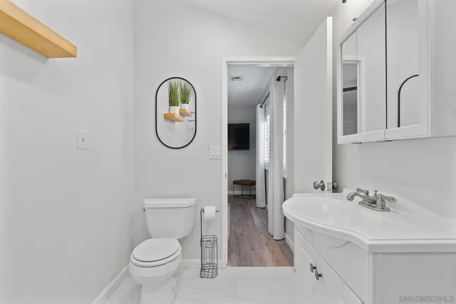 a bathroom with a granite countertop toilet sink and mirror