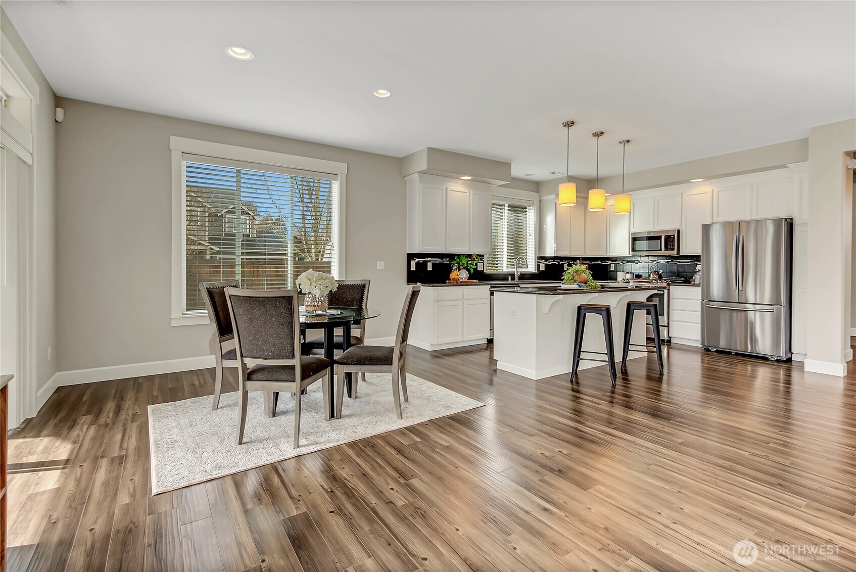 14925 Benton Loop Sumner, WA 98390 - Photo 16 of 40 a kitchen with stainless steel appliances granite countertop wooden floor dining table and chairs