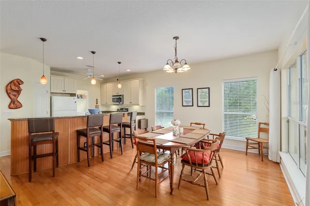 a open kitchen with stainless steel appliances granite countertop a stove top oven a sink dishwasher a dining table and chairs with wooden floor