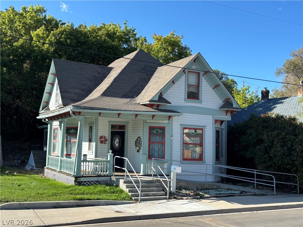 Victorian-style house featuring a porch and roof with shingles