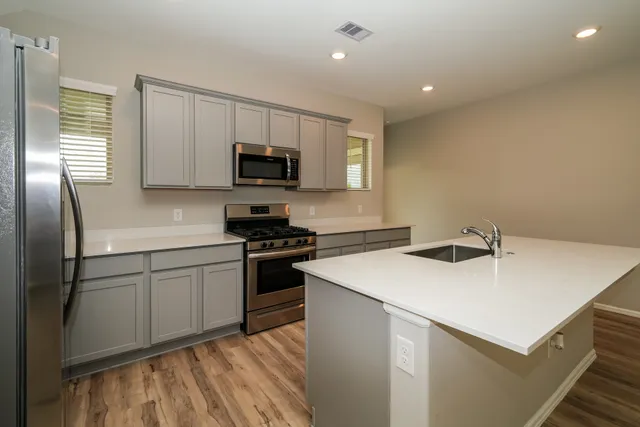 a kitchen with a sink a stove a microwave and white cabinets