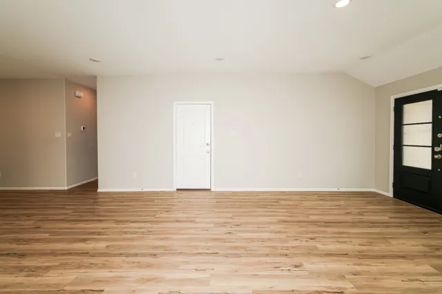 a view of an empty room with window and wooden floor