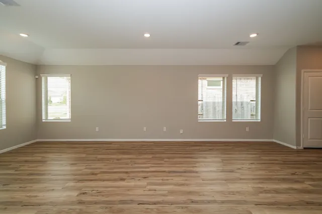a view of an empty room with window and wooden floor
