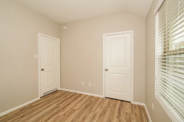 a view of an empty room with wooden floor and a window