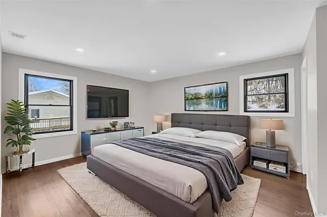 a bedroom with a large bed a flat tv screen and a potted plant