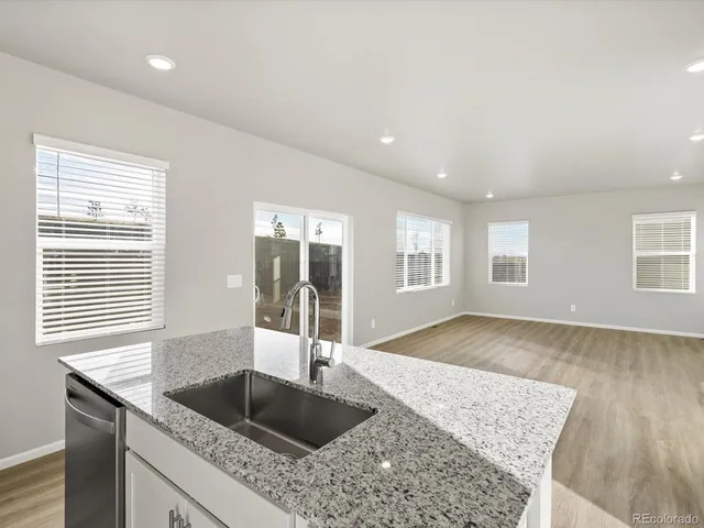 a kitchen with granite countertop a sink and a wooden floor