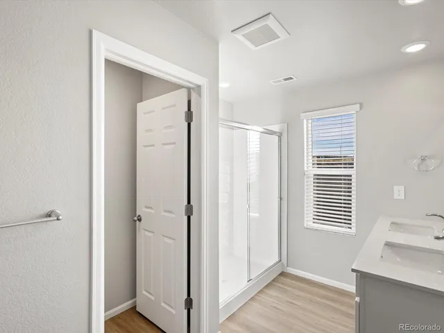 a view of a hallway with wooden floor and a bathroom