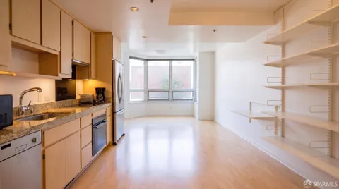 a kitchen with stainless steel appliances a sink dishwasher a stove a refrigerator and cabinets with wooden floor