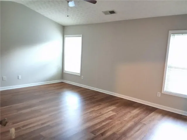 an empty room with wooden floor and windows