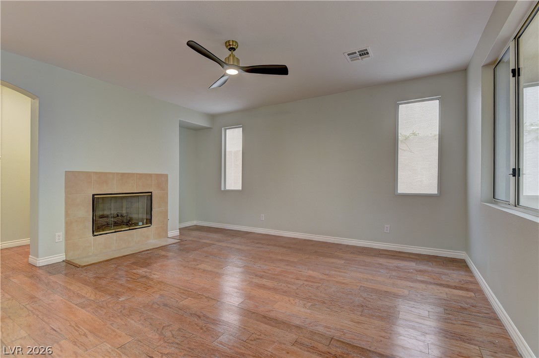 1813 Snow Spring Lane Las Vegas, NV 89134 - Photo 17 of 37 A welcoming living space features a tiled fireplace, rich wood flooring, and a contemporary ceiling fan.