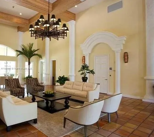 a living room with couches chandelier and a table with potted plants