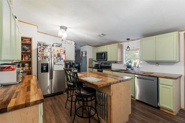 a kitchen with stainless steel appliances granite countertop a sink a stove a refrigerator and island with wooden floor