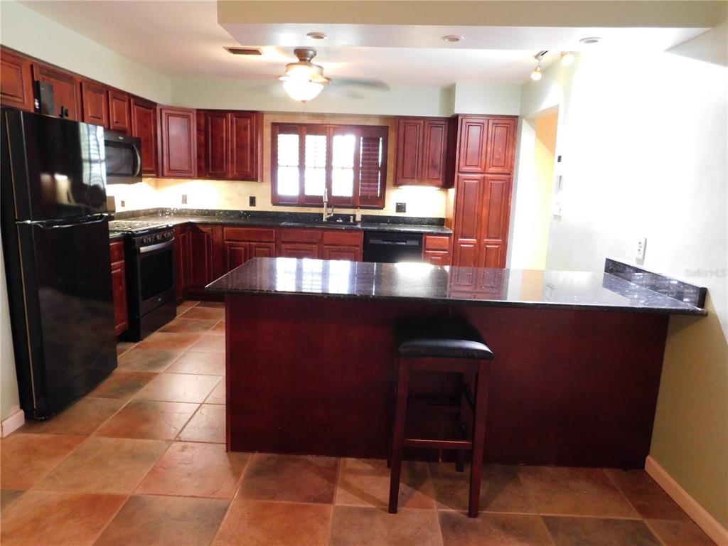888 Forest Glen Road Clearwater, FL 33765 - Photo 11 of 61 a kitchen with stainless steel appliances granite countertop a refrigerator a sink dishwasher a stove a dining table and chairs with wooden floor