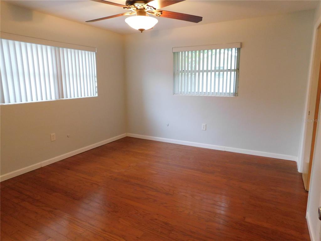 888 Forest Glen Road Clearwater, FL 33765 - Photo 22 of 61 an empty room with wooden floor fan and windows