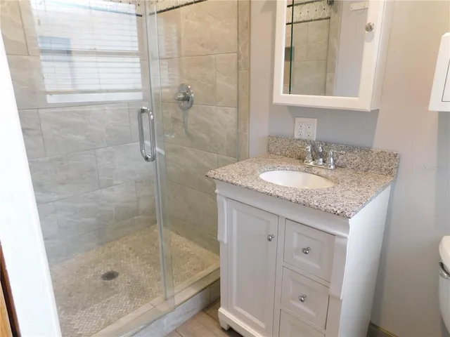 a bathroom with a granite countertop shower a sink and a mirror