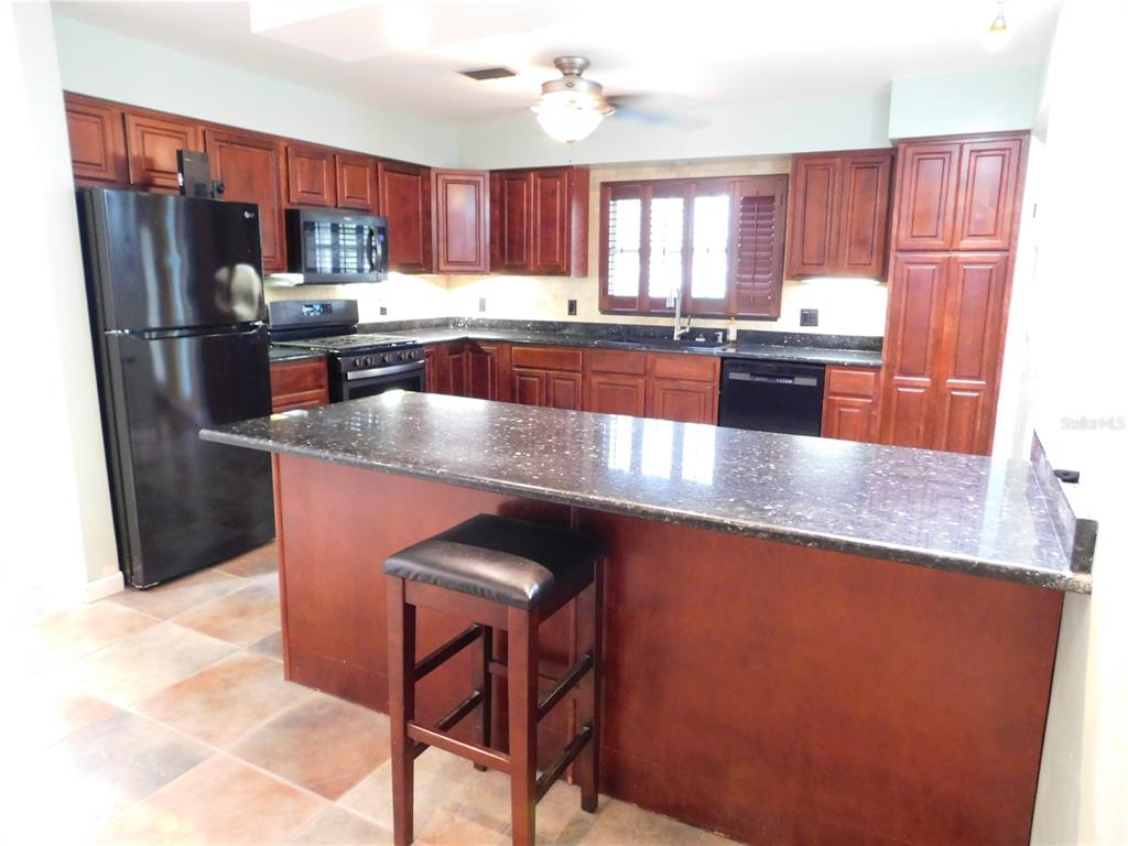 888 Forest Glen Road Clearwater, FL 33765 - Photo 6 of 61 a kitchen with stainless steel appliances granite countertop a refrigerator a sink a stove a dining table and chairs
