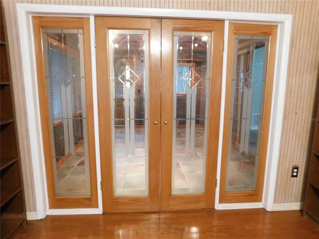 a kitchen with stainless steel appliances granite countertop a refrigerator a sink dishwasher a stove a dining table and chairs with wooden floor