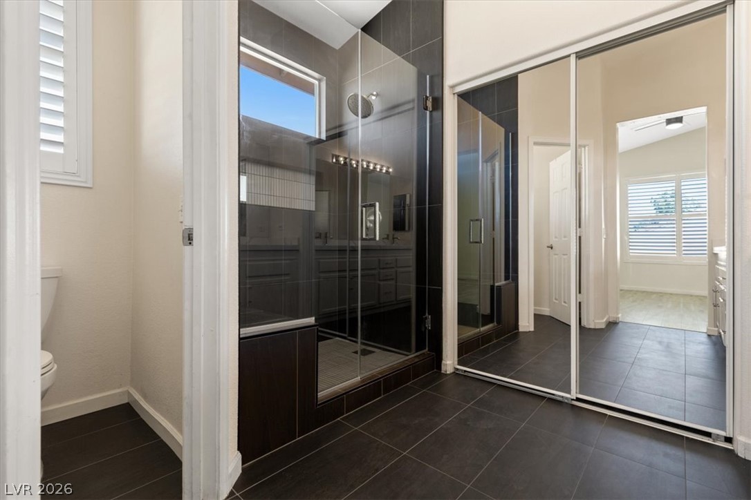 1007 Golden Ridge Court Henderson, NV 89052 - Photo 16 of 27 Dark tile floors and a glass-enclosed shower define this modern bathroom layout.