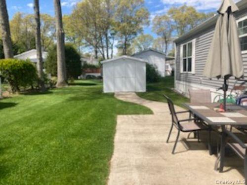 1661 Old Country Road, Unit 49 Riverhead, NY 11901 - Photo 5 of 11 a view of a backyard with table and chairs and a barbeque with potted plants