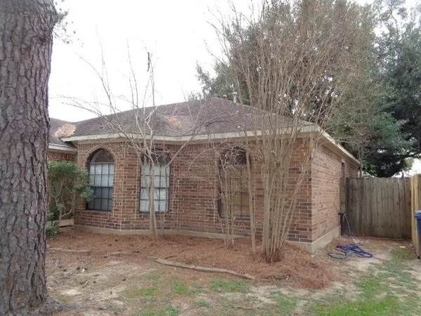 a view of a wooden house with a large tree and wooden fence