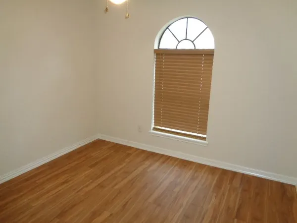 an empty room with wooden floor and a window