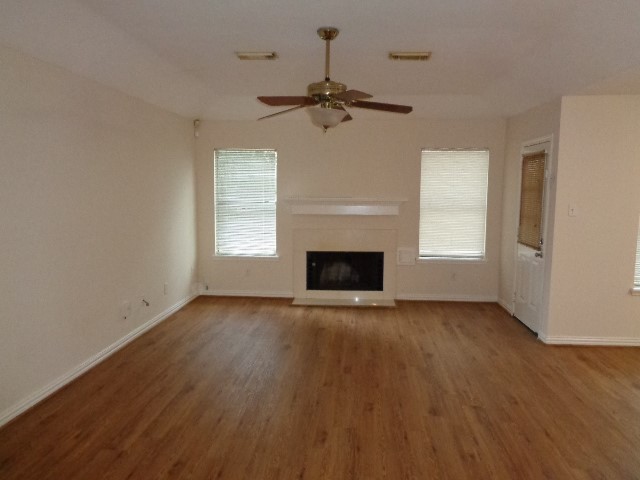 17823 Poppy Trails Lane Houston, TX 77084 - Photo 6 of 22 an empty room with wooden floor fireplace and windows