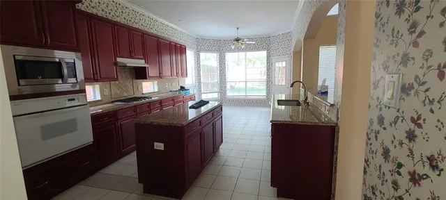 a kitchen with stainless steel appliances granite countertop a stove a sink and a microwave