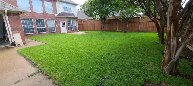 a view of a backyard with white house and large trees