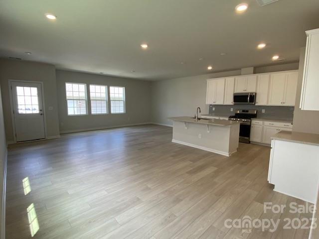 933 Cobbled Way, Unit 35 Fort Mill, SC 29715 - Photo 16 of 30 a kitchen with stainless steel appliances a stove a sink a refrigerator white cabinets and a wooden floor