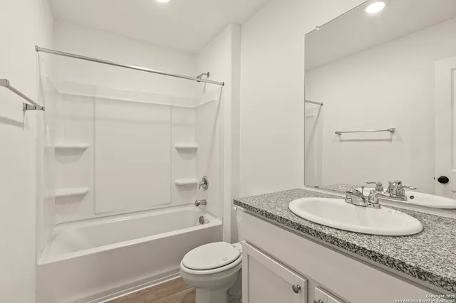 a bathroom with a granite countertop sink a toilet and shower