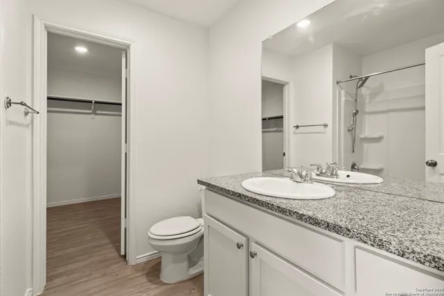 a bathroom with a granite countertop sink a toilet and a mirror