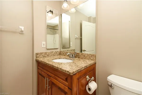a bathroom with a granite countertop sink and a mirror with toilet