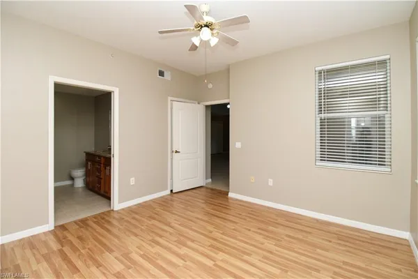 a view of empty room with wooden floor and fan