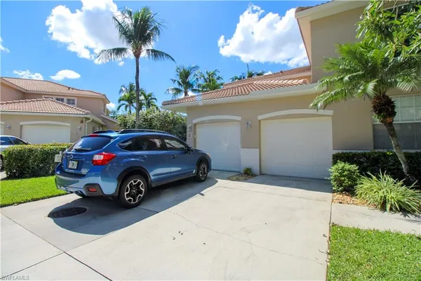 a view of a house with a cars park side of a road