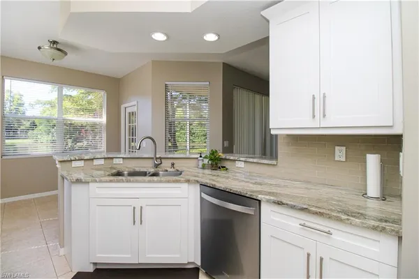 a kitchen with kitchen island granite countertop a sink window and cabinets