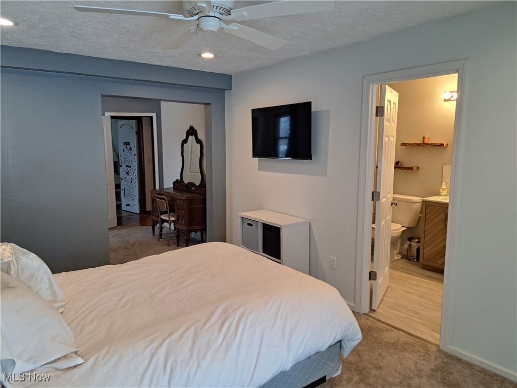 3813 State Road Vermilion, OH 44089 - Photo 18 of 28 Carpeted bedroom featuring a closet, ceiling fan, ensuite bathroom, and a textured ceiling