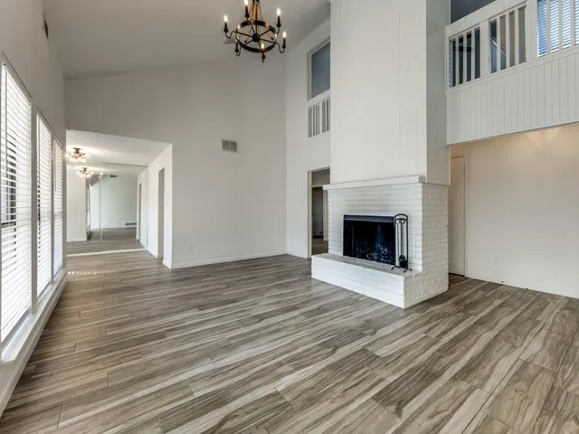 a view of an empty room with wooden floor and a fireplace