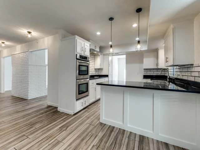 a kitchen with stainless steel appliances granite countertop a sink a stove and a wooden floors