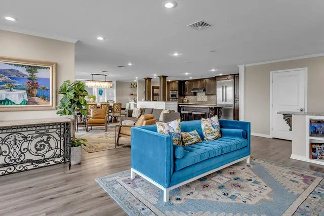 a living room with stainless steel appliances furniture and a kitchen view