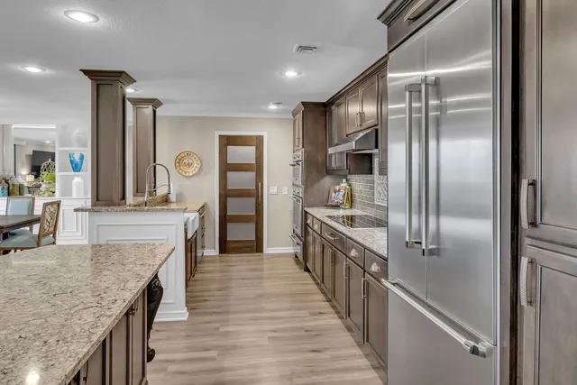a large kitchen with kitchen island a large counter top and stainless steel appliances