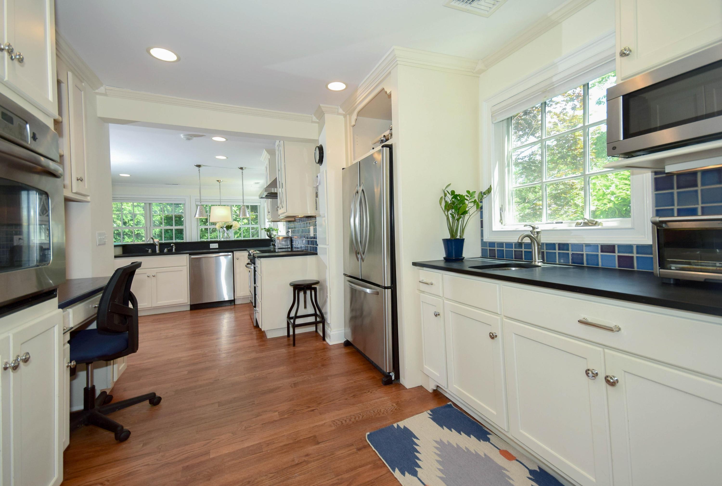 35 Ridgeley Street Darien, CT 06820 - Photo 8 of 25 a kitchen with stainless steel appliances granite countertop a refrigerator a stove a sink dishwasher a dining table and chairs with wooden floor