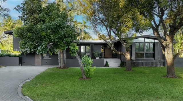 a front view of a house with garden and trees